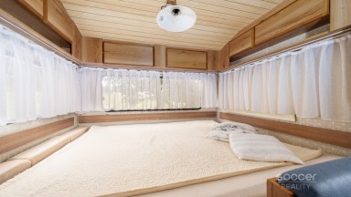 Příjemná venkovská zahrada s rekreačním karavanem a terasou.